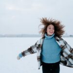 Woman with Curly Hair Running Through Snow Field