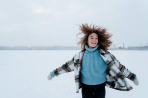 Woman with Curly Hair Running Through Snow Field